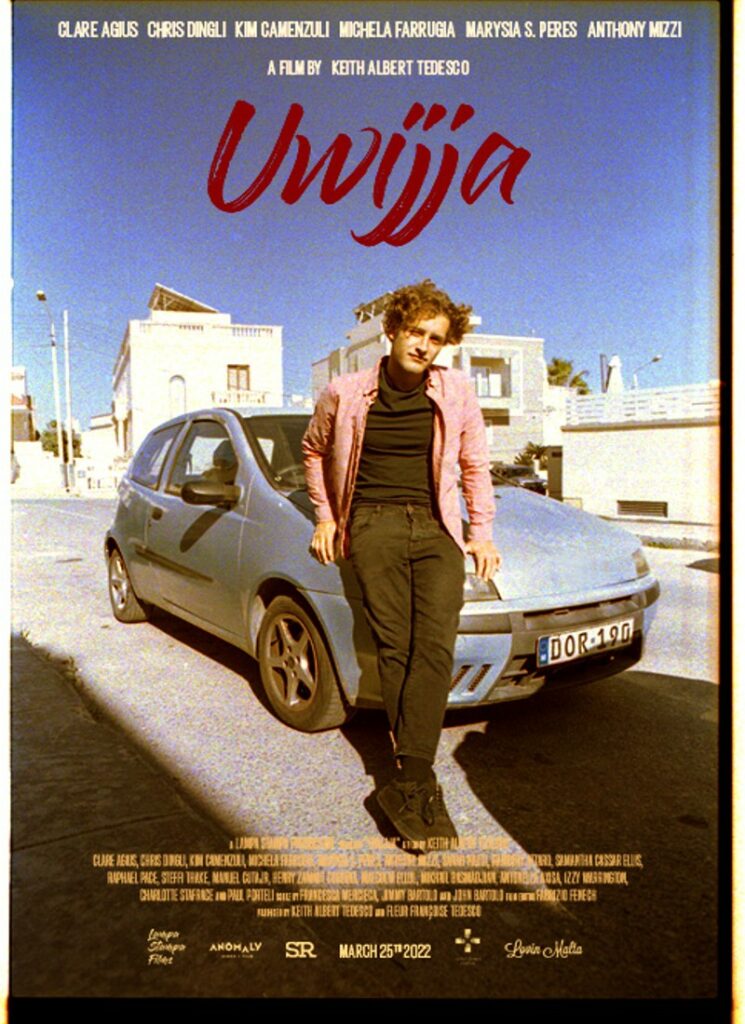 Young man standing in front of his blue car